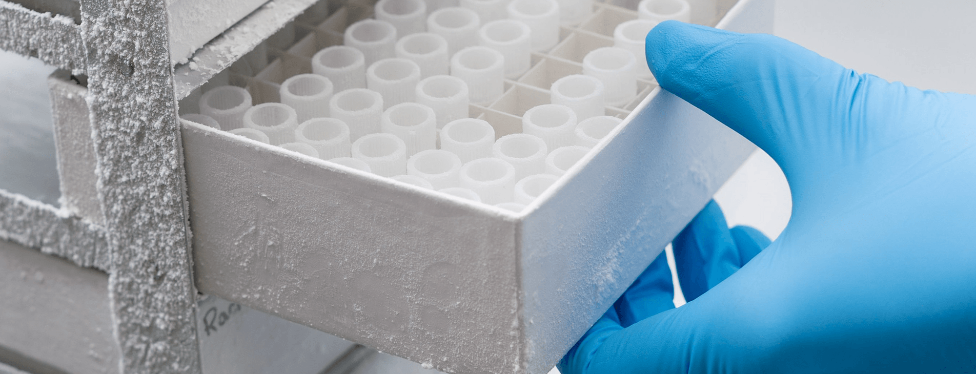 a hand in a rubber glove pulls vials from a drawer